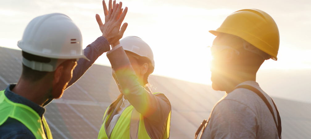 Engineers High-Fiving in front of Commercial Solar Panel